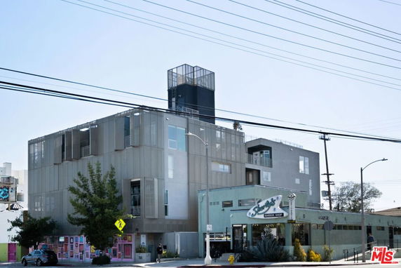 Front view of a modern multi-story building with a barber shop on the ground floor.