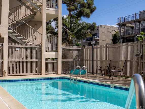 Outdoor swimming pool area with a fence and nearby stairway.
