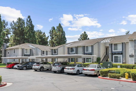 Outdoor parking area in front of residential buildings with covered parking spaces.