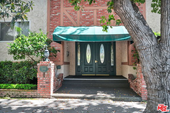 Front view of a building entrance with a green awning and double doors.