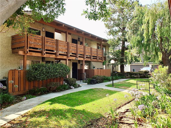 Front view of a two-story building with wooden balconies and a landscaped path.