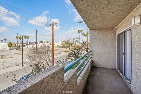 View from a balcony overlooking an urban area with power lines and palm trees.
