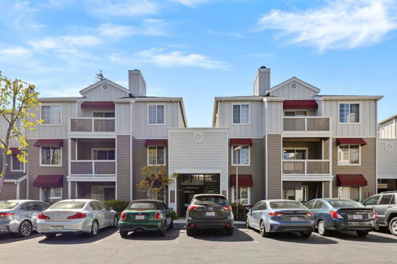 Front view of a multi-story residential building with parking area.