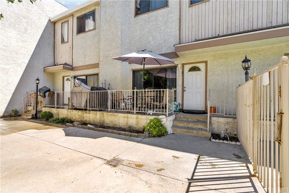 Front view of a multi-story building with a small patio area and an entrance door.