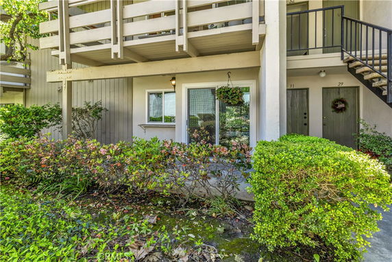 Front view of a multi-story building with an entrance and balconies, surrounded by greenery.