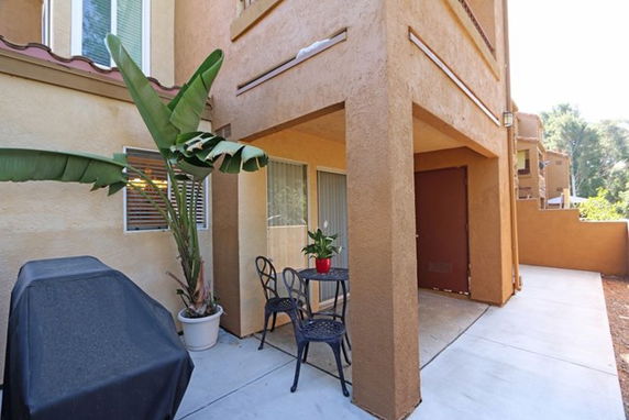 Outdoor view of a multi-story house with a small patio area.
