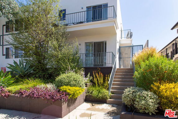 Front view of a two-story house with a balcony and stairs leading to the entrance.