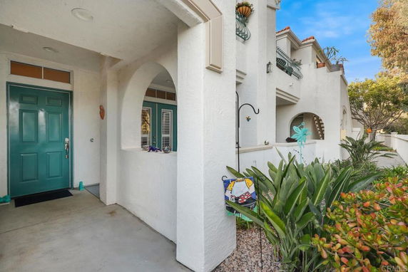 Front view of a multi-story house with a teal front door and arched entryway.