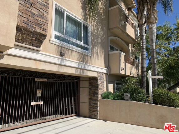Front view of a multi-story building with balconies and a gated entry.