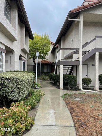 Pathway between buildings with staircase leading to the upper floor.