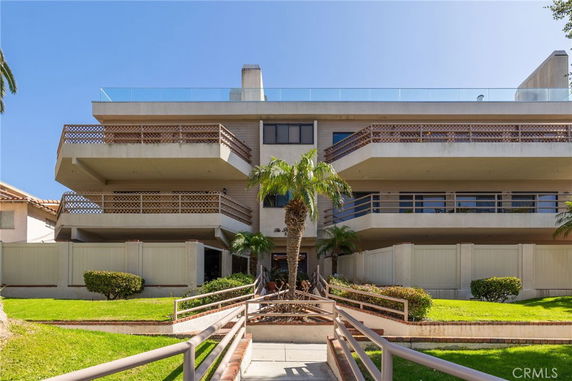 Front view of a multi-story residential building with balconies and railing.