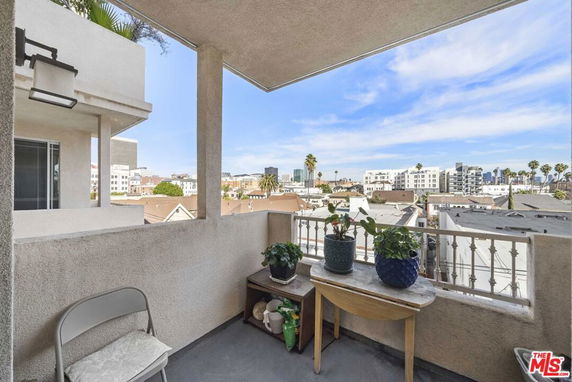 Balcony view overlooking urban residential area with buildings and palm trees visible.