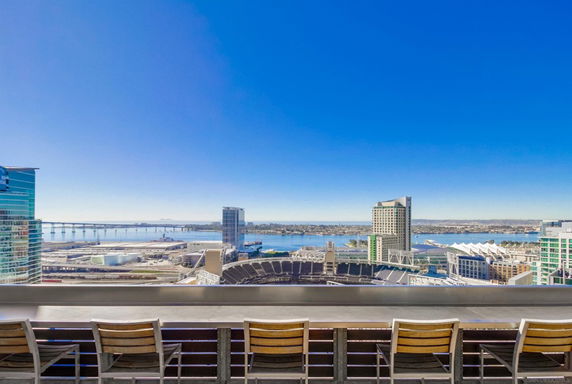Panoramic view of a cityscape with skyscrapers and water bodies in the background, seen from a rooftop or terrace.