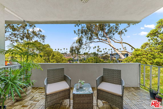 Balcony view overlooking trees and distant buildings.