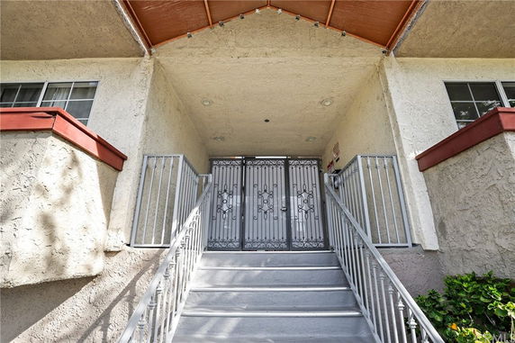 Front view of a building entrance with iron gates and stairs leading up.