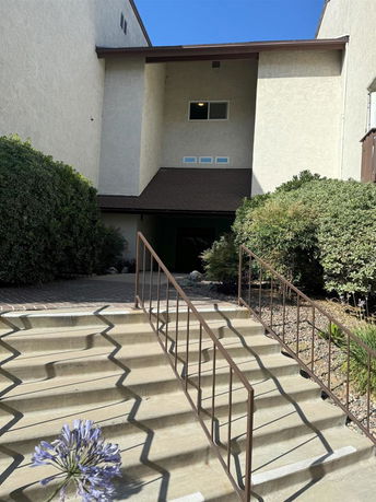 Front view of a building with multiple small windows and a staircase leading to the entrance.