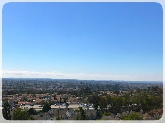 Panoramic view of residential area and distant landscape under a clear blue sky.