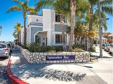 Front view of a two-story building with a stone wall and palm trees.