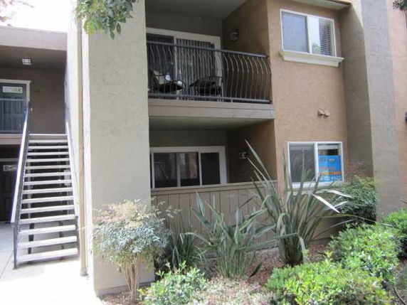 Front view of a multi-story apartment building with exterior stairs and balcony.