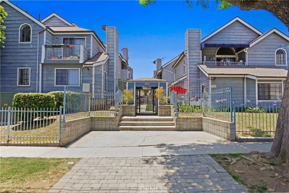 Front view of a multi-story residential building with balconies and a gated entrance.