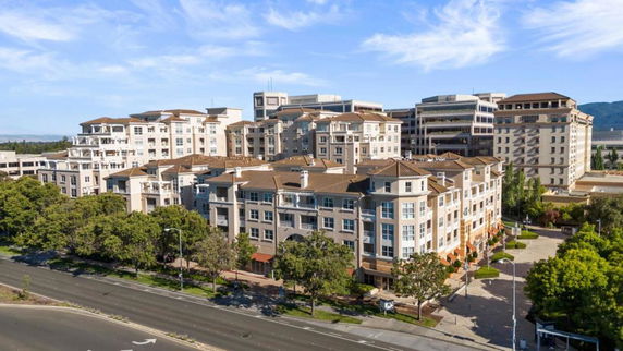 Front view of a multi-story apartment complex with tan and white exterior.