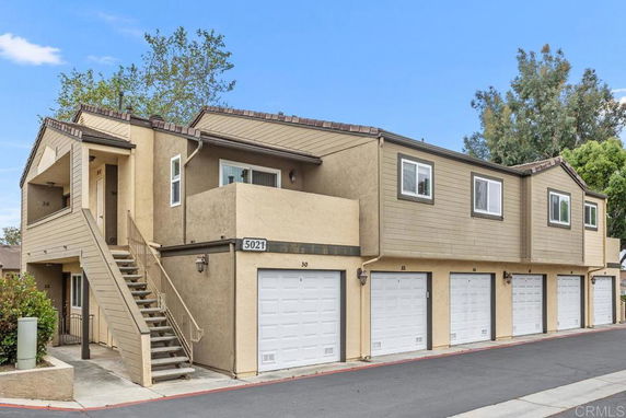 Front view of a two-story building with multiple garage doors and an external staircase.