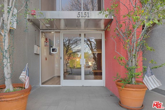 Front entrance of a building with glass doors and potted plants.