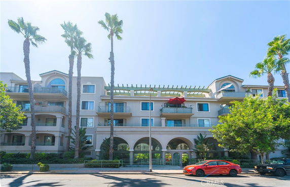 Front view of a multi-story residential building with balconies and an arched entrance.