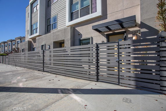 Front view of a multi-story residential building with modern design and fenced entrance.