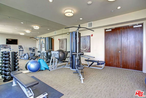 Indoor gym area with exercise equipment and mirrored walls.