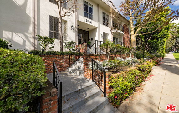 Front view of a multi-story building with brick accents and a staircase leading to the entrance.