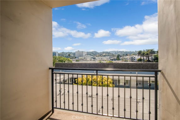 View from a balcony looking out over city buildings and rolling hills in the distance.