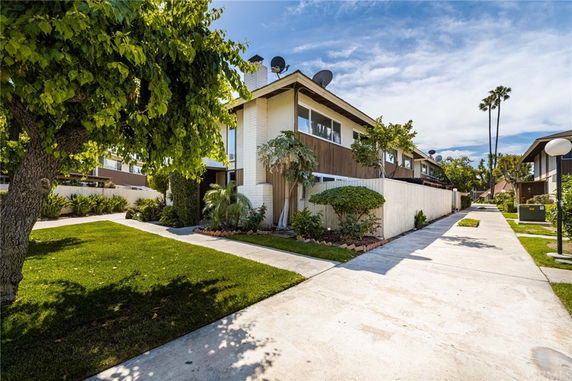Front view of a two-story residential building with a pathway and landscaped front yard.