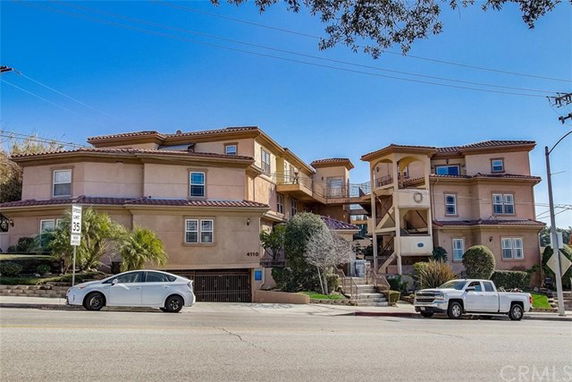 Front view of a multi-story residential building with tiled roofs and balconies.