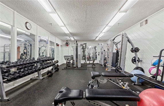 Indoor gym area with various exercise equipment and mirrors on the walls.