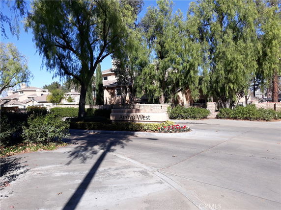 Front view of a residential building with signage reading Arroyo West, surrounded by trees.