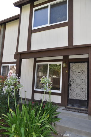Front view of a house with brown and white paneling and a decorative front door.