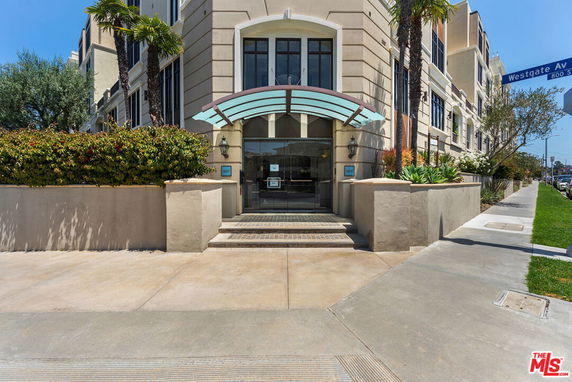 Front view of a multi-story building entrance with an arched glass canopy.