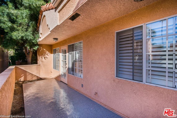 Side view of a building with stucco walls and french doors.