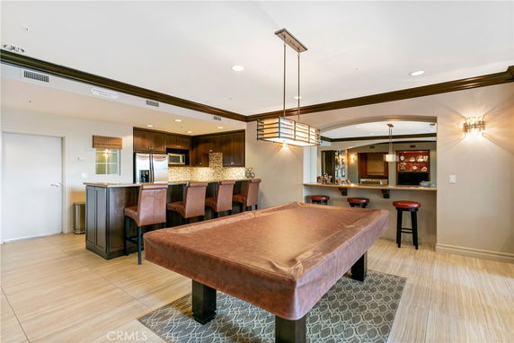 Interior view of a recreational room with a pool table and bar seating.