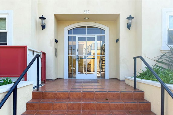 Front view of a building entrance with tiled steps and glass doors.