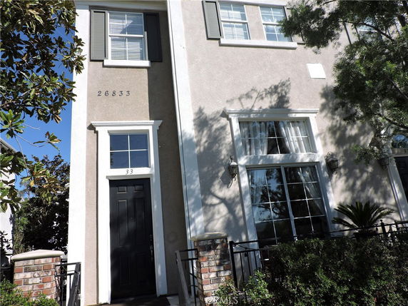 Front view of a multi-story house with large windows and a dark front door.