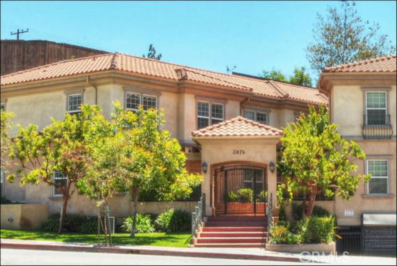 Front view of a two-story house with a tiled roof and gated entrance.