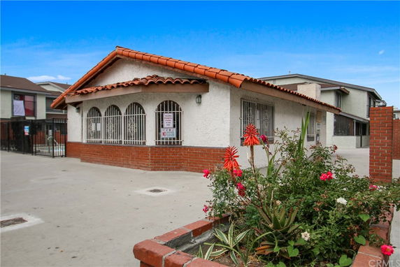 Front view of a single-story building with a red tile roof and barred windows.