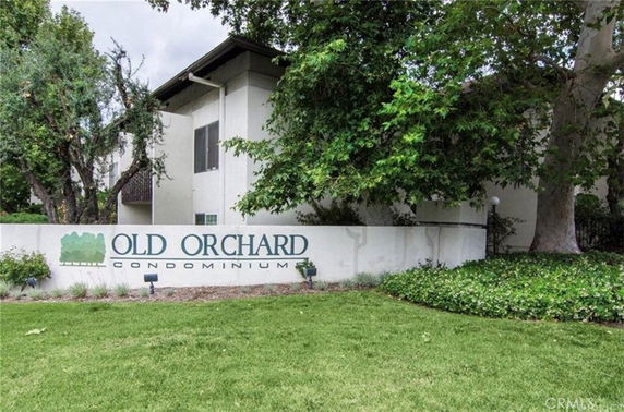 Front view of a condominium building with a sign that reads 'Old Orchard Condominium'.