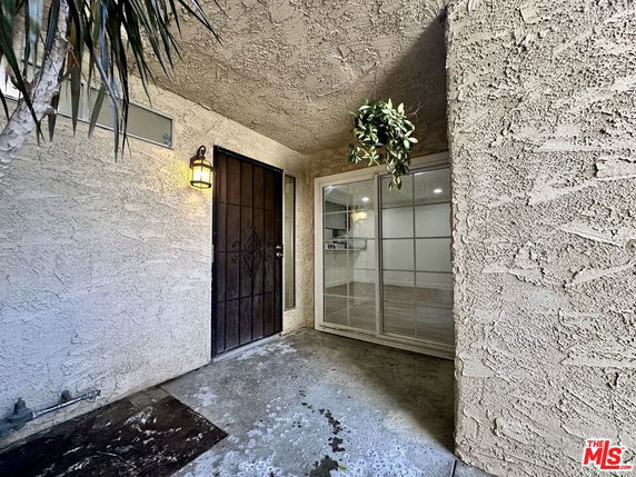 Front entrance of a house with a metal door and sliding glass door.