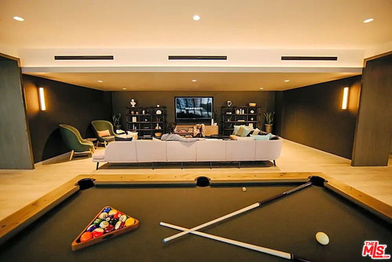 Room with a pool table and seating area with a TV.