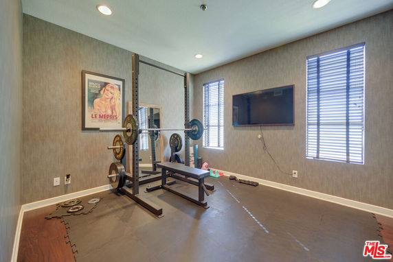 Indoor gym area with weightlifting equipment and TV on the wall.