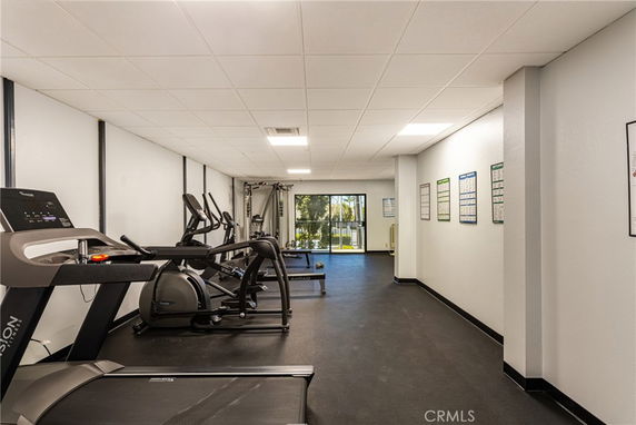 Interior view of a fitness area with gym equipment and posters on the walls.