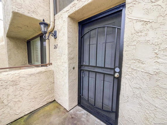 Front view of a building entrance with a metal security door and stucco walls.